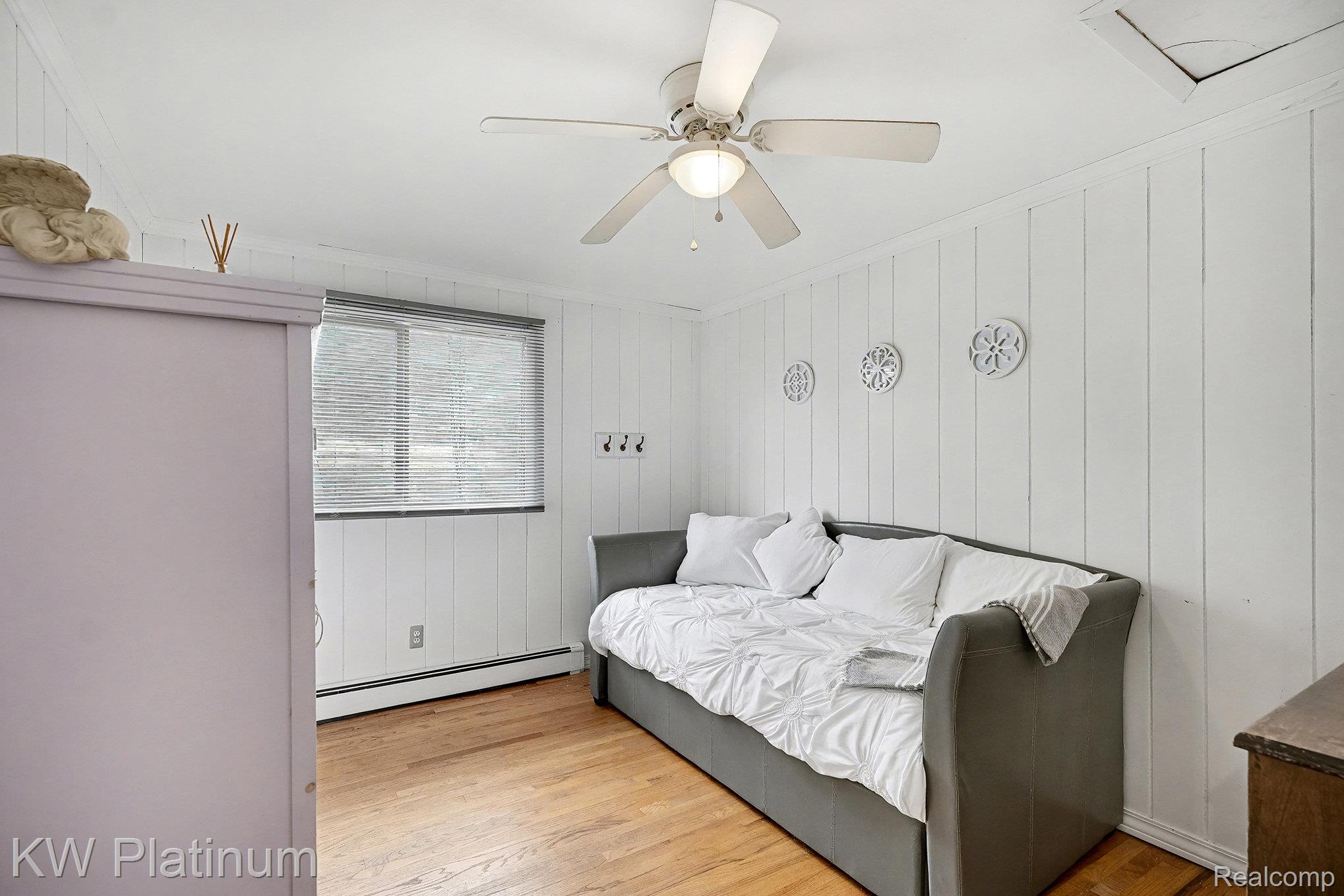 185 Michelson Road Rochester, MI 48307 - Photo 19 of 36 Bedroom with a baseboard heating unit, light wood-type flooring, ornamental molding, a ceiling fan, and wooden walls
