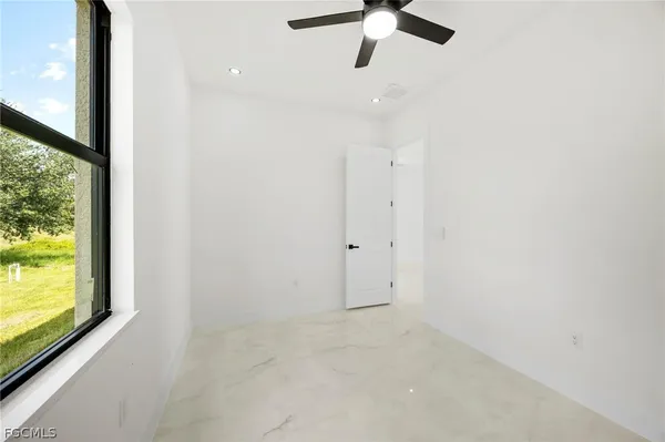 an empty room with a window and a fan