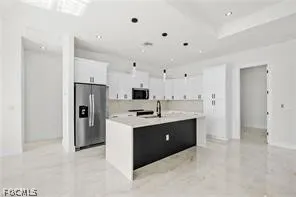 a view with kitchen island a refrigerator a sink dishwasher with a stove and cabinets