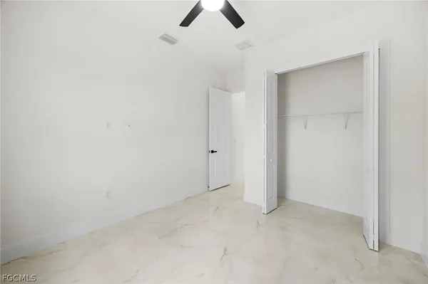 an empty room with ceiling fan and window