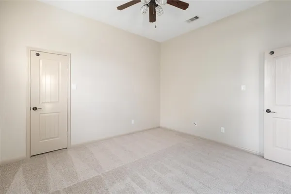 an empty room with a ceiling fan and carpet