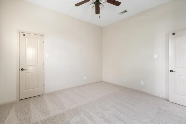 an empty room with a ceiling fan and carpet