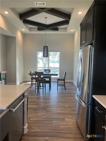 a kitchen with stainless steel appliances granite countertop a refrigerator a stove and a dining table with wooden floor