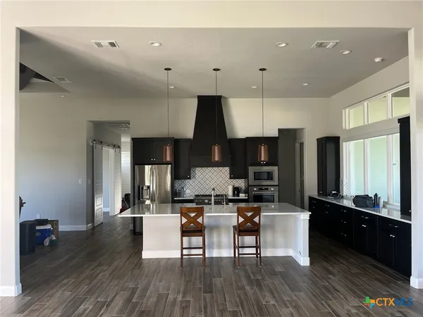a living room with stainless steel appliances kitchen island granite countertop furniture and a wooden floor