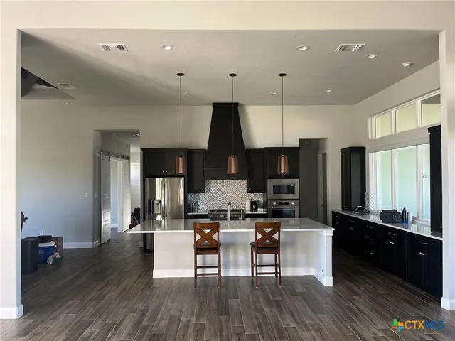 a living room with stainless steel appliances kitchen island granite countertop furniture and a wooden floor