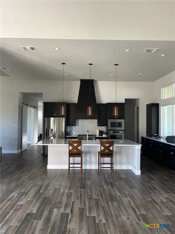a living room with stainless steel appliances furniture and wooden floor