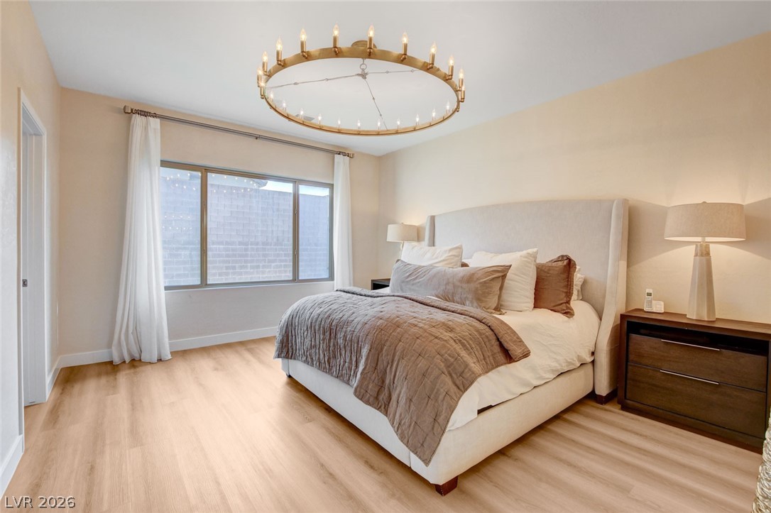 2649 Rue Marquette Avenue Henderson, NV 89044 - Photo 41 of 55 This serene sleeping space features wide plank flooring and a distinctive circular chandelier, creating an inviting atmosphere.