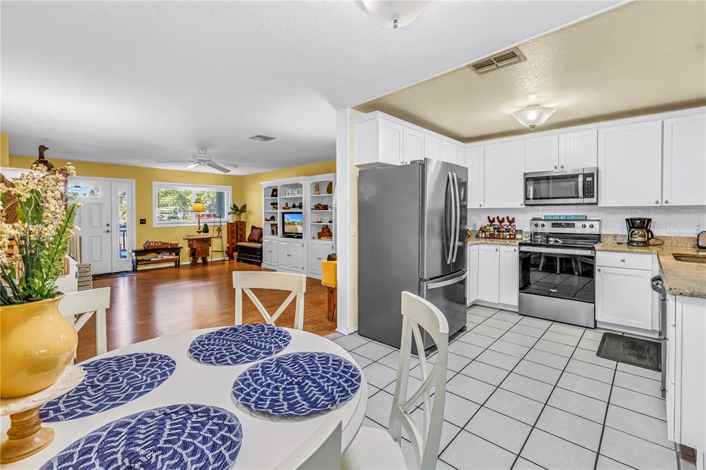 10020 Panama Court Seminole, FL 33776 - Photo 8 of 25 a kitchen with stainless steel appliances granite countertop a refrigerator a stove top oven a sink dishwasher and dining table with wooden floor