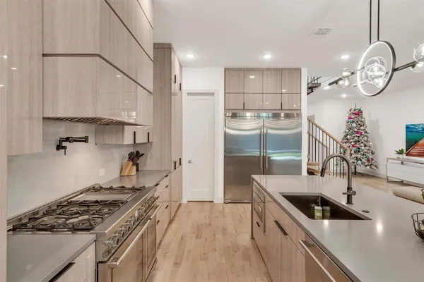 a kitchen with stainless steel appliances a stove a sink a counter top space and living room view