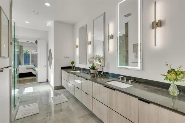 a large white bathroom with a double vanity sink a mirror and a shower
