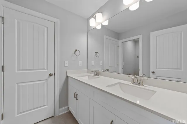 a bathroom with double vanity sinks and a mirror