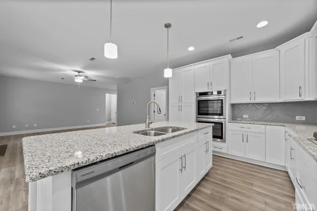 a kitchen with kitchen island granite countertop a sink white cabinets and stainless steel appliances