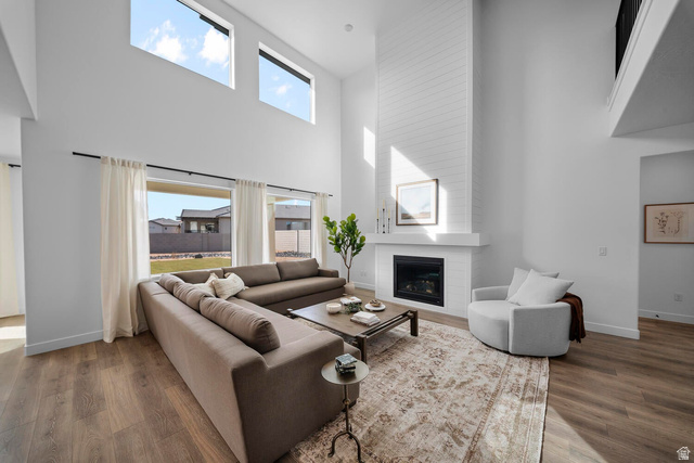382 North Rhyolite Drive, Unit 111 Hurricane, UT 84737 - Photo 2 of 37 Living area featuring high ceilings, wood-finish flooring, a contemporary fireplace with a white shiplap surround, a built-in mantel, and large windows
