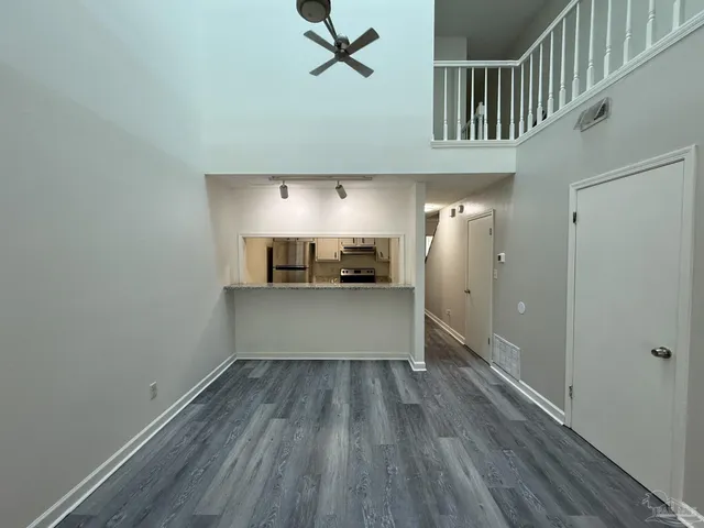 a view of a hallway with wooden floor and a kitchen