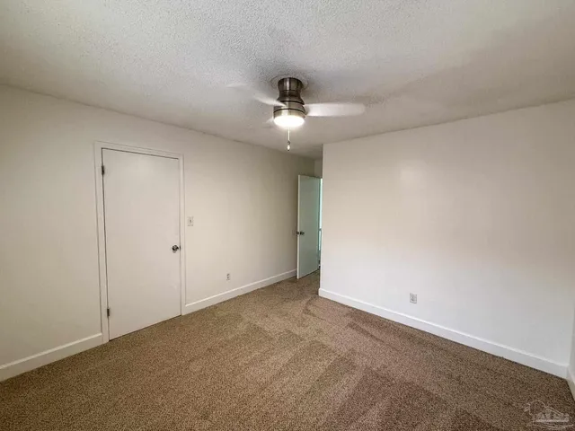 an empty room with a ceiling fan and a window