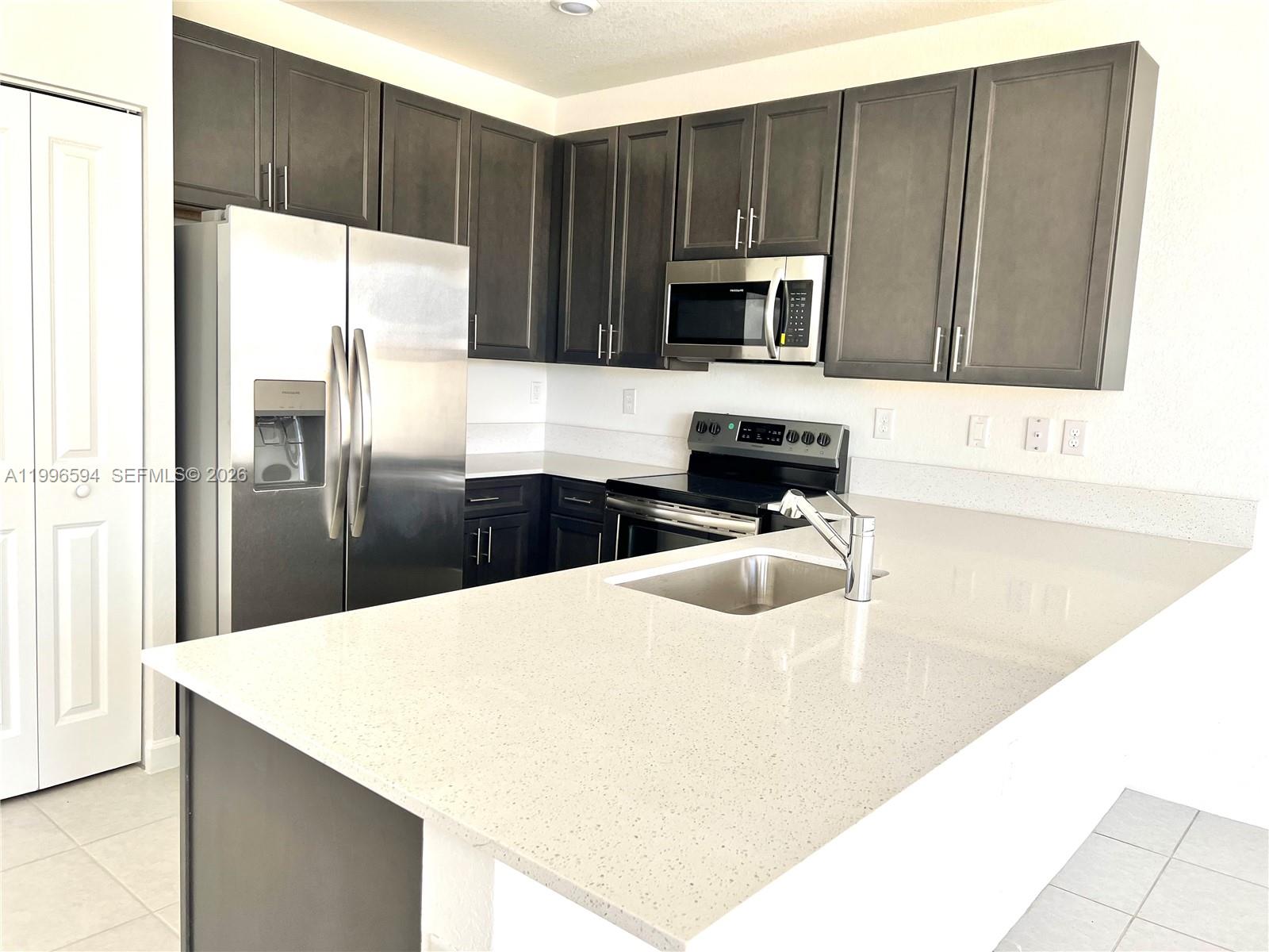 23373 Southwest 129th Path, Unit 23373 Homestead, FL 33032 - Photo 9 of 18 a kitchen with stainless steel appliances wooden cabinets a refrigerator and a sink
