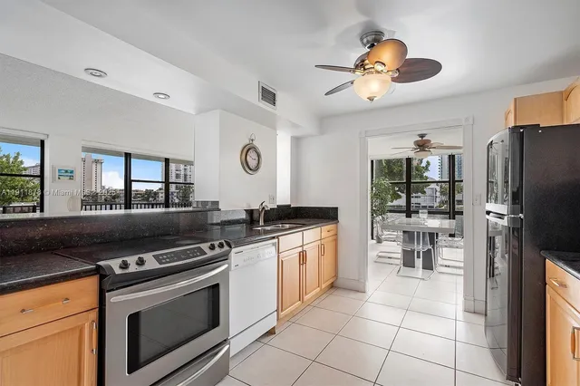 a kitchen with stainless steel appliances granite countertop a refrigerator a stove and a sink