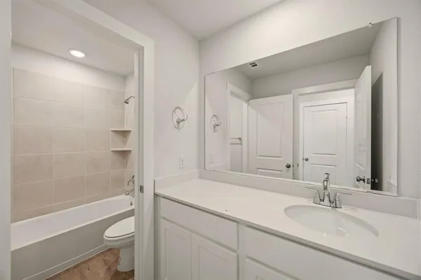a bathroom with a bathtub shower sink vanity and toilet