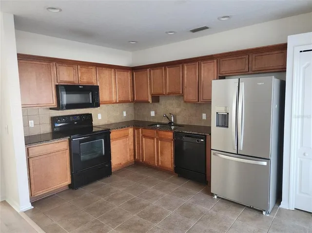 a kitchen with granite countertop a refrigerator stove and microwave