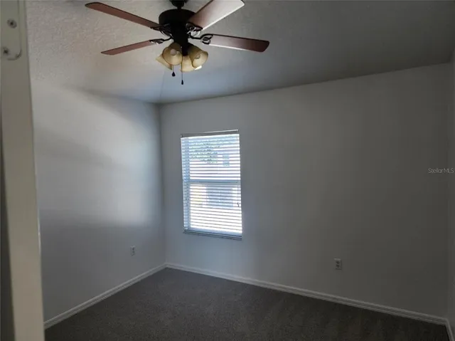 an empty room with a window and a fan