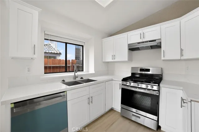 a kitchen with white cabinets appliances and a sink