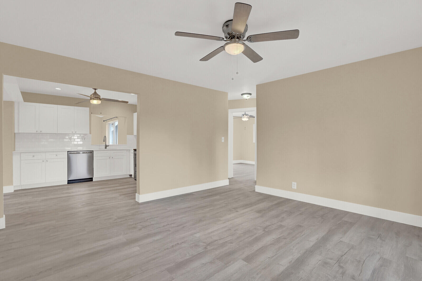 101 Northwest 9th Street Boca Raton, FL 33432 - Photo 9 of 35 an empty room with wooden floor ceiling fan and kitchen view