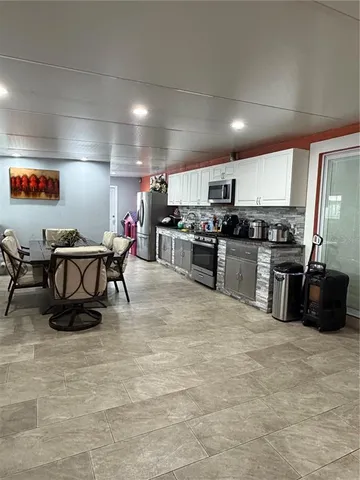 a kitchen with stainless steel appliances granite countertop a stove top oven a sink a dining table and chairs with wooden floor