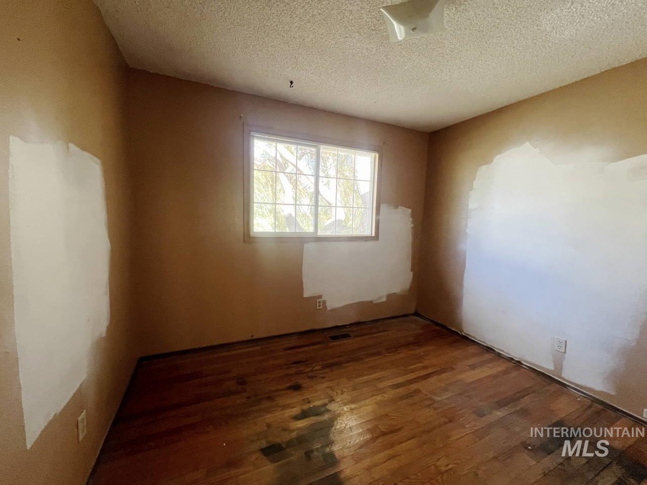 905 West Adams Street Garfield, WA 99130 - Photo 10 of 19 Spare room featuring wood-type flooring and a textured ceiling