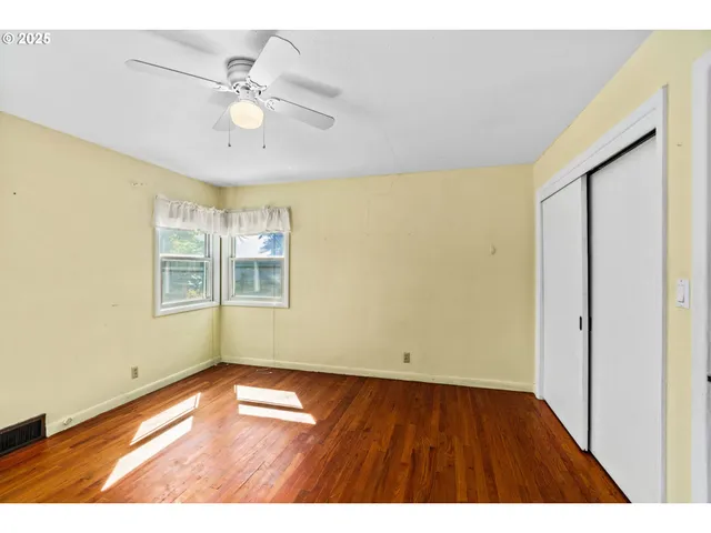 a view of an empty room with window and wooden floor