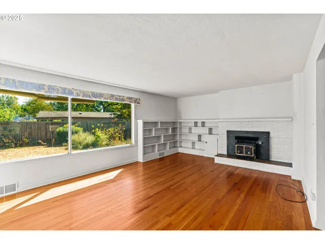 a view of an empty room with a fireplace and a window