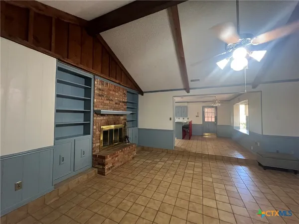 a view of a livingroom with a fireplace a chandelier wooden floor and windows