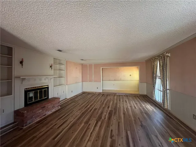 a view of empty room with a fireplace and wooden floor