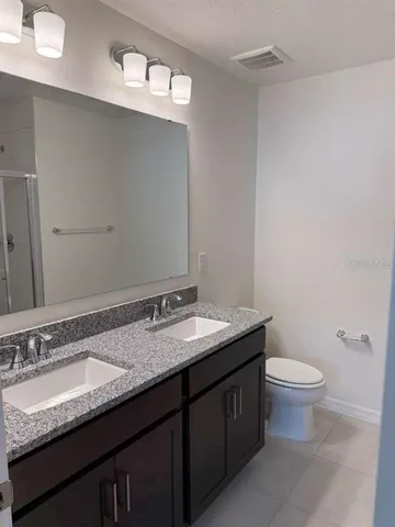 a bathroom with a granite countertop sink a toilet and a mirror