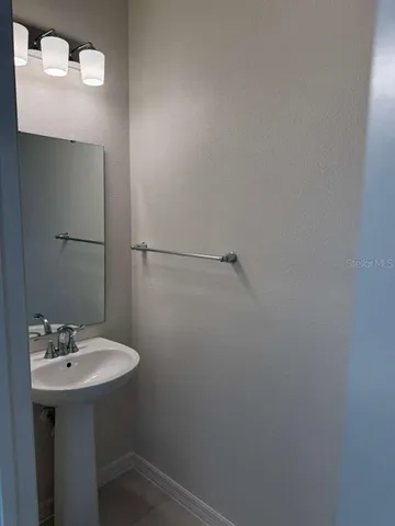 a bathroom with a sink a light fixture and a mirror