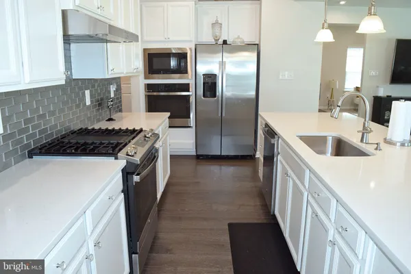 a kitchen with a sink a counter top space stainless steel appliances and cabinets