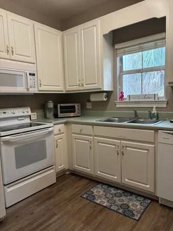 a kitchen with granite countertop white cabinets and white appliances