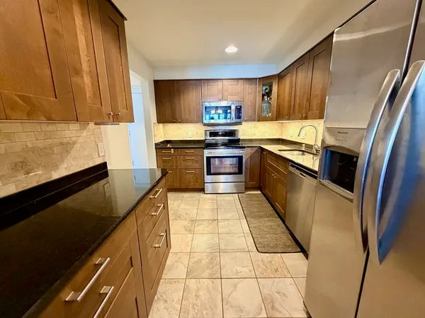 a kitchen with stainless steel appliances granite countertop a refrigerator and a stove