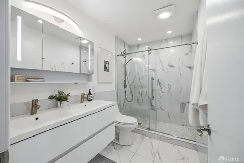 a bathroom with a shower sink vanity mirror and toilet