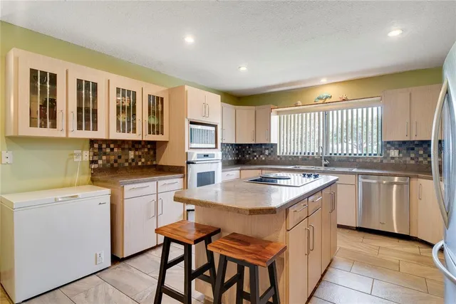 a kitchen with a stove a sink a microwave a refrigerator and cabinets