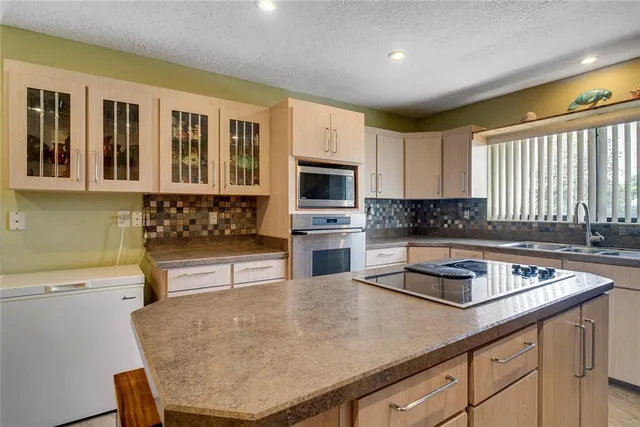 a kitchen with stainless steel appliances granite countertop a sink window and cabinets
