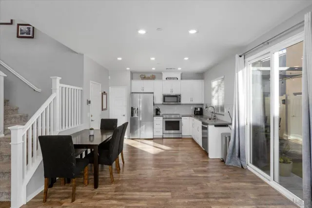 a kitchen with stainless steel appliances kitchen island granite countertop a dining table chairs refrigerator and sink