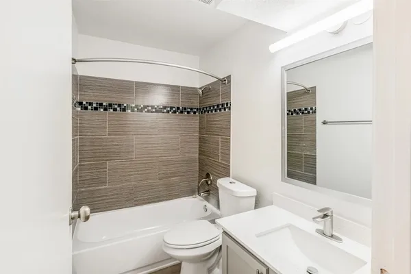 a bathroom with a bathtub shower sink vanity mirror and toilet