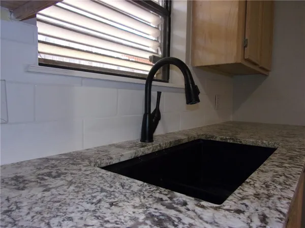a kitchen with granite countertop a sink and a white wooden cabinets