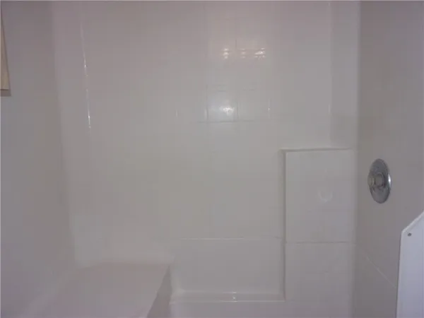an empty room with a chandelier fan and windows