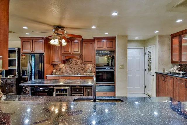 a kitchen with kitchen island granite countertop a refrigerator a oven a stove and a refrigerator