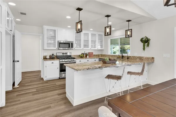 a dining room with wooden floor a chandelier a wooden table and chairs