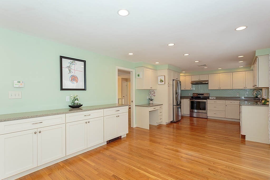 130 Worthen Road Lexington, MA 02421 - Photo 10 of 27 a large kitchen with white cabinets a sink dishwasher a stove and a refrigerator with wooden floor