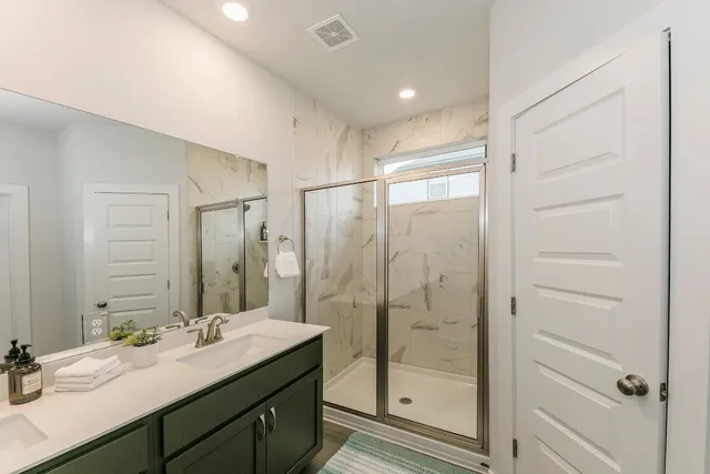 a bathroom with a double vanity sink mirror and shower