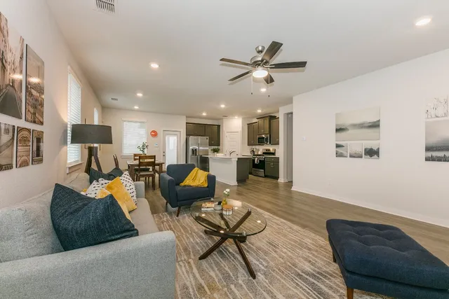 a living room with furniture kitchen view and a wooden floor