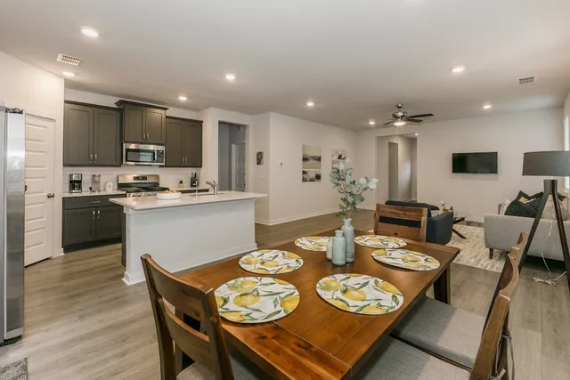 a open dining room with stainless steel appliances kitchen island granite countertop a dining table and chairs with wooden floor